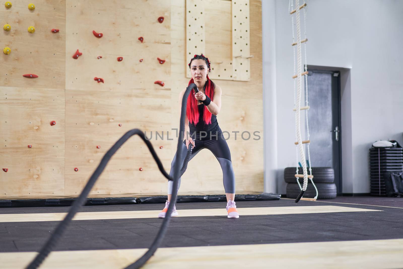 Gym battle rope woman stamina training Athlete guy fitness exercising endurance indoor workout. Handsome caucasian sportive guy doing exercise functional training fitness. Muscular men naked torso
