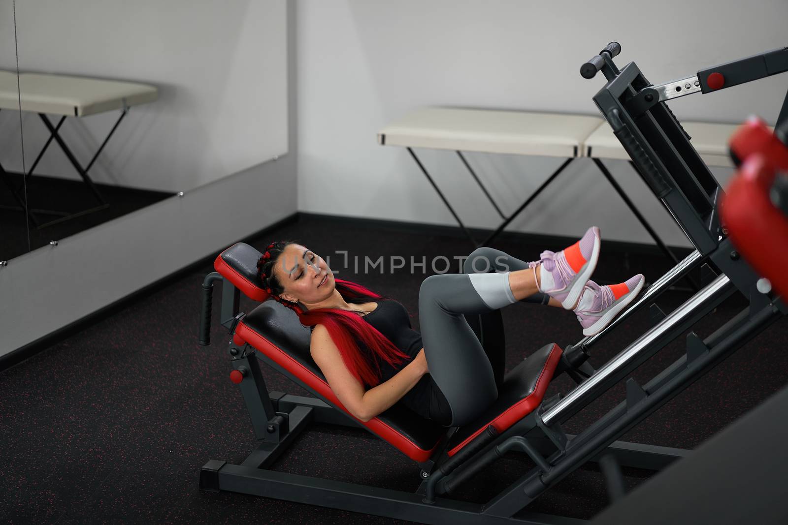 Gym woman leg press machine training pushing weight Handsome caucasian middle age girl training define his upper legs muscule cross training indoors. Make your body.