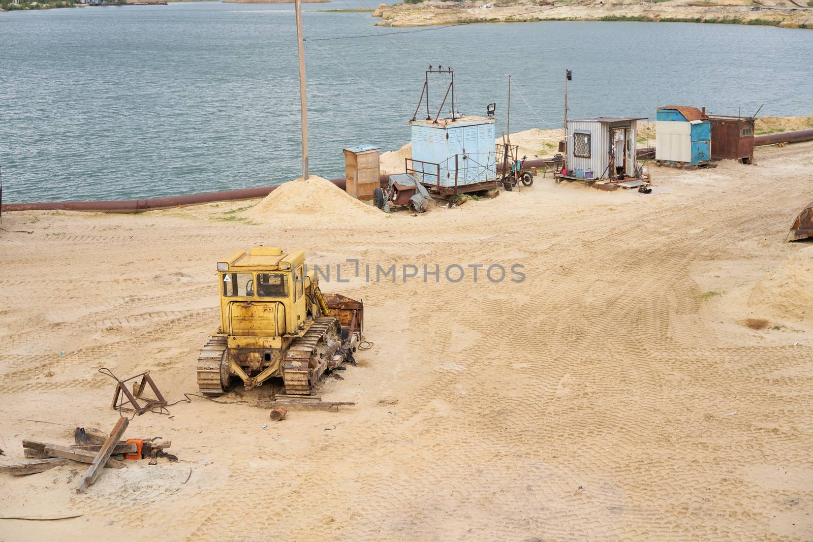 Sand quarry mining industry equipment excavator tractor standing sand land near lake water Industrial activity mine operation summer sunny day. Ecology problem Non-renewable resources of the Earth
