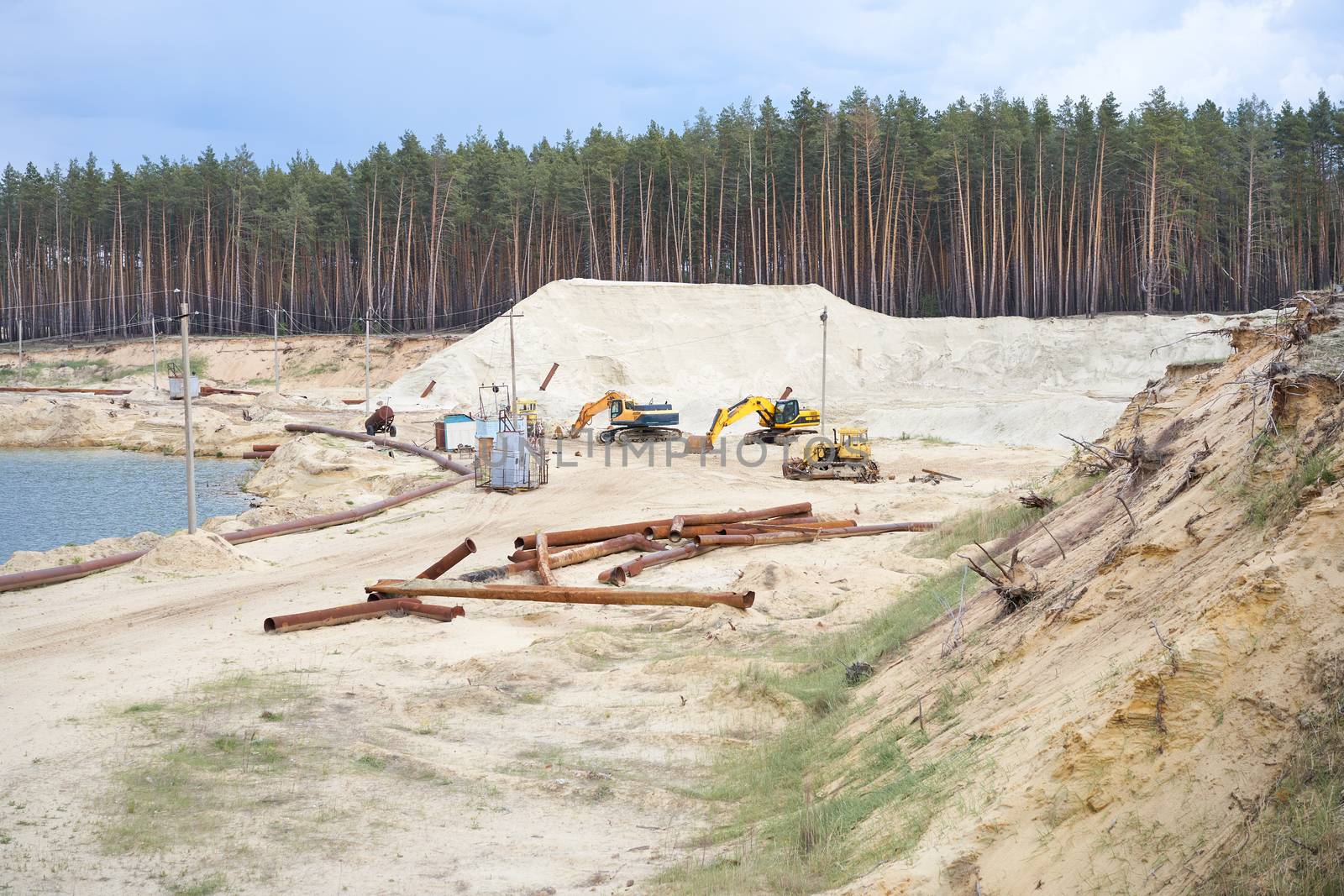 Sand quarry mining industry equipment excavator tractor standing sand land near lake water Industrial activity mine operation summer sunny day. Ecology problem Non-renewable resources of the Earth