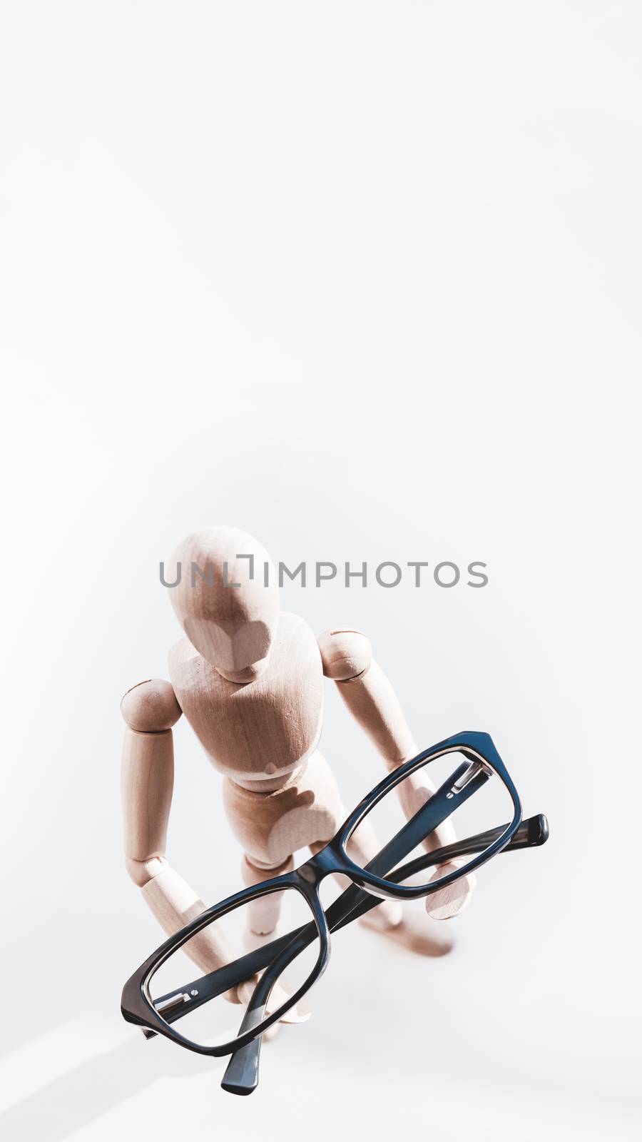 Wooden dummy with eyeglasses in hands. Mannequin presents glasses as a help for comfort life in case of poor vision. Miniature model of human as concept symbol of ophthalmology. by aksenovko