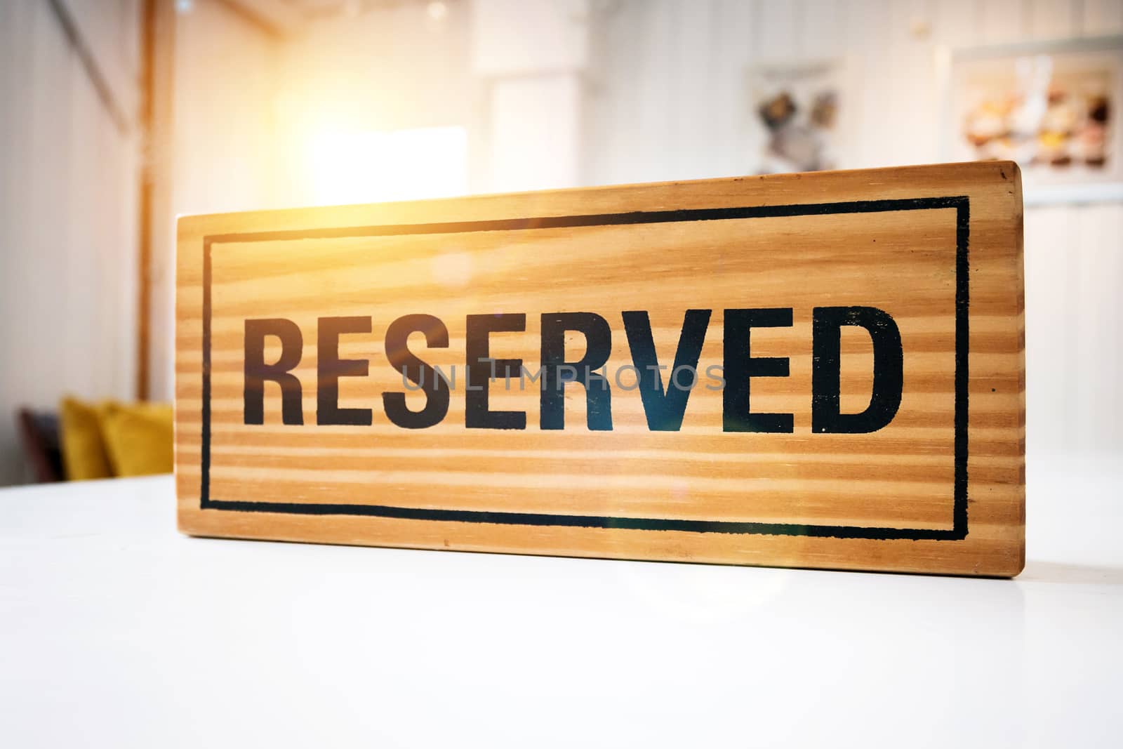Reservation seat at restaurant for dating on celebrate day concept. Restaurant with reserved wooden sign on white table with cafe decorate places setting and evening light with bokeh for dinner time by asiandelight