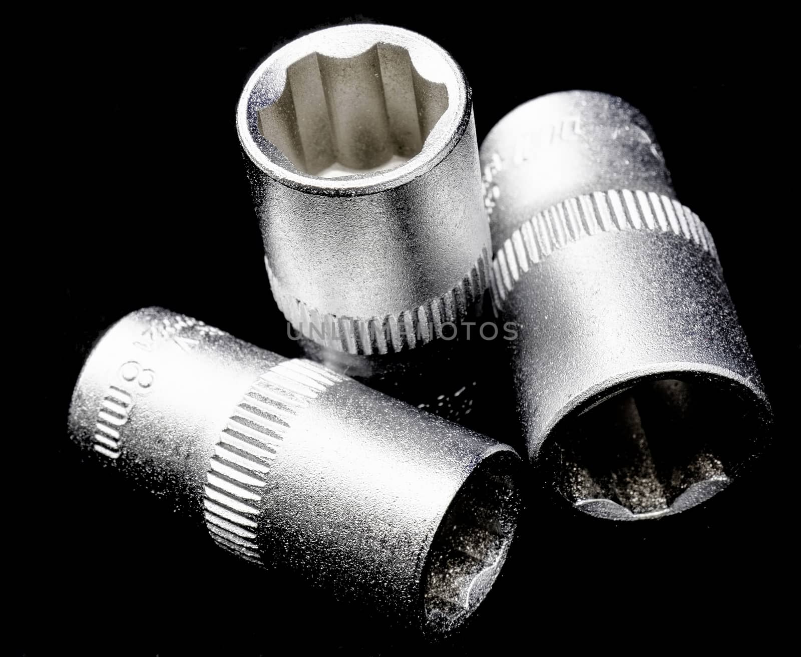Three Wrench inserts, blurred and with strict illumination, black background