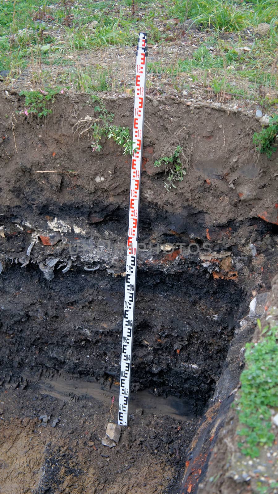 Former rubbish dump in the excavation pit, black discoloured and contaminated soil, old deposit in a construction area for residential buildings