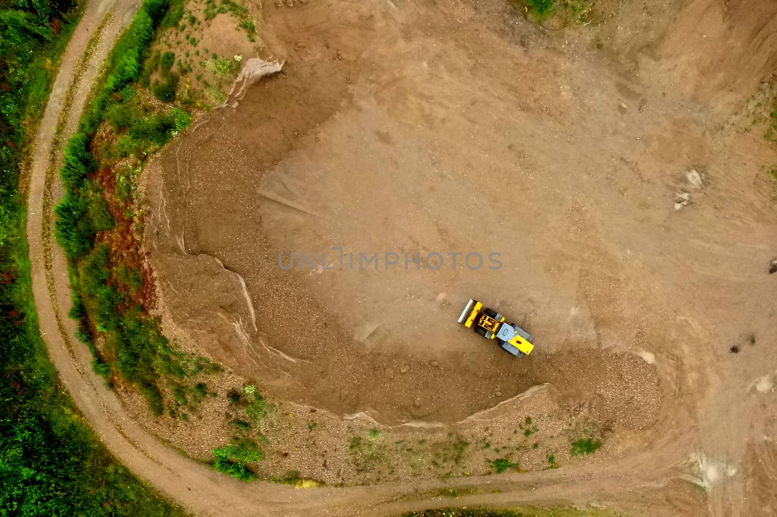 Aerial view of a spoil heap with a sickle-shaped geometry and a wheel loader, made by drone