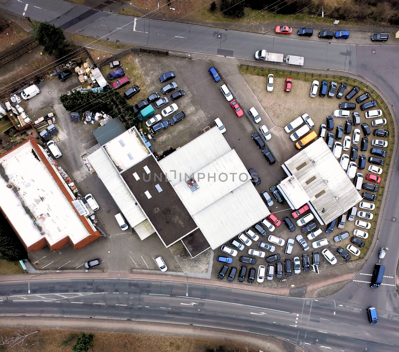 Aerial view of an industrial estate with many parking cars between two roads at the edge of a city, drones shot