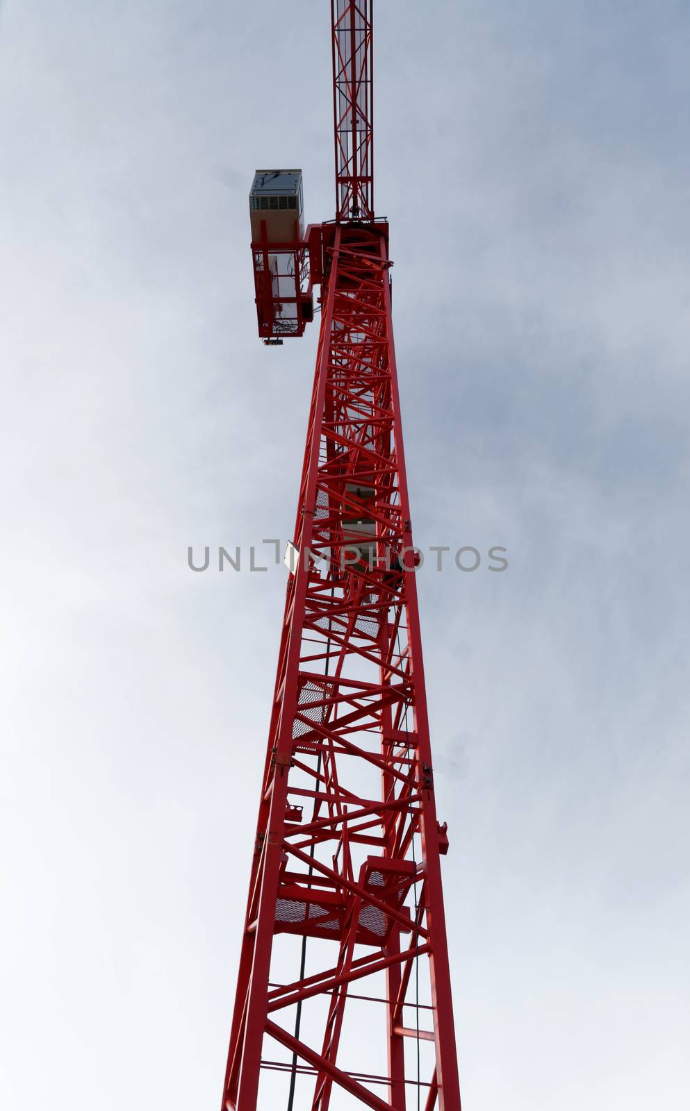 Red high construction crane on a building site, oblique picture of an abstract image effect, dramatic sky.