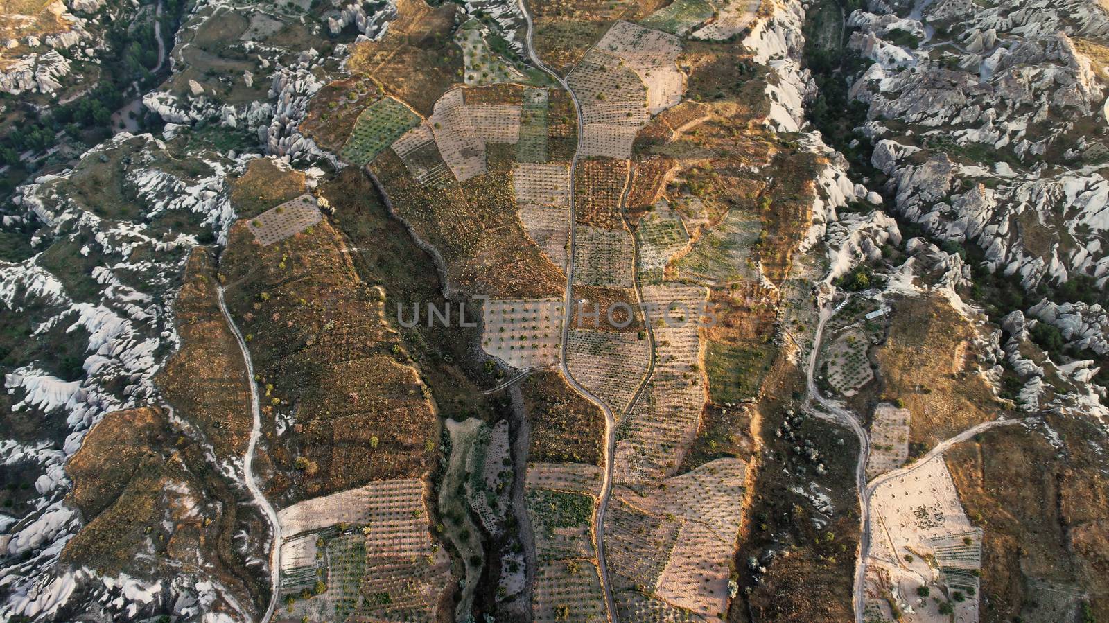 Aerial view of small vegetable fields between the craggy cliffs of Cappadocia, Anatolia, Turkey, from the hot air balloon