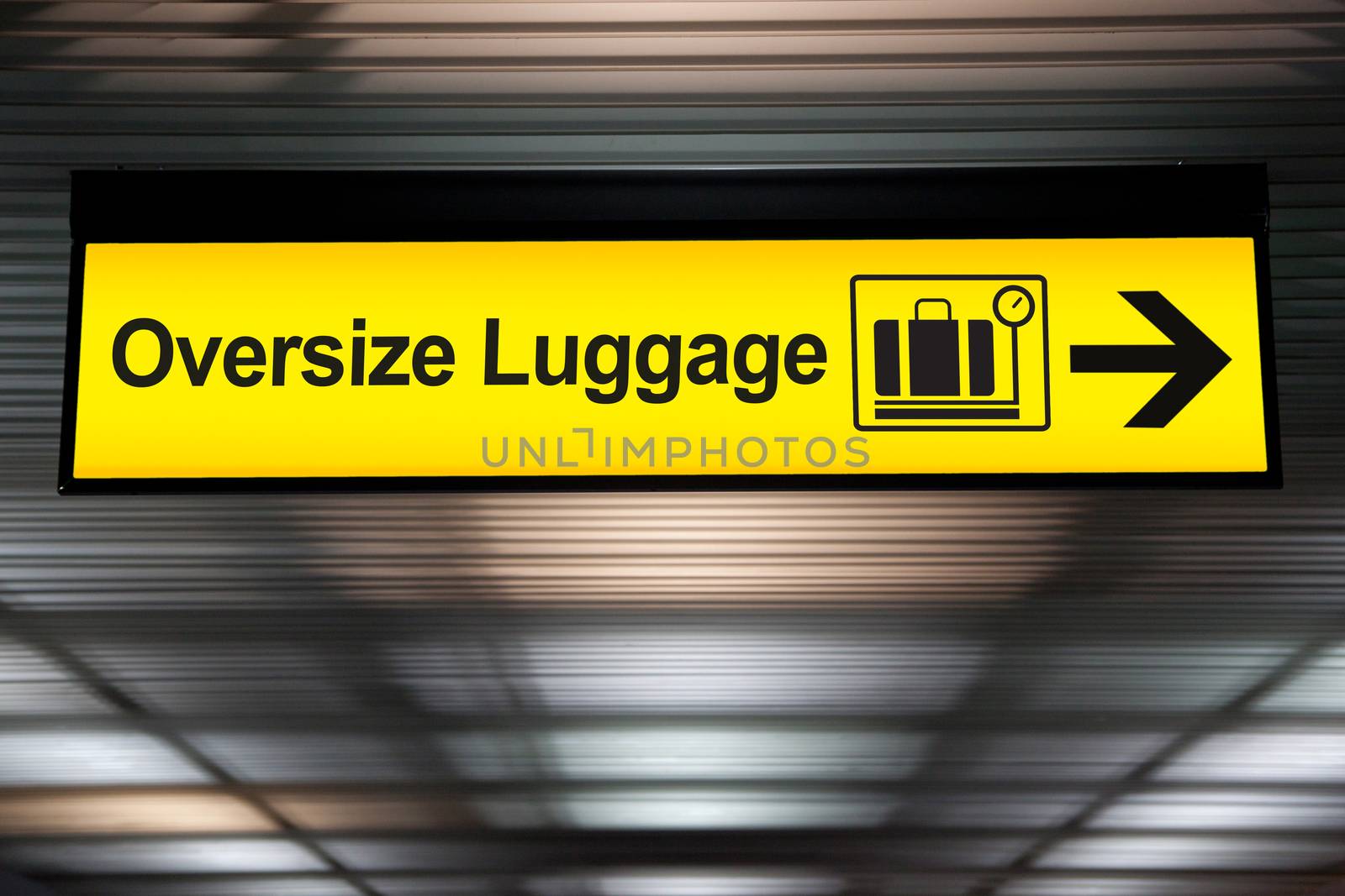 oversize luggage yellow sign with arrow direction hang from ceiling at the airport by asiandelight