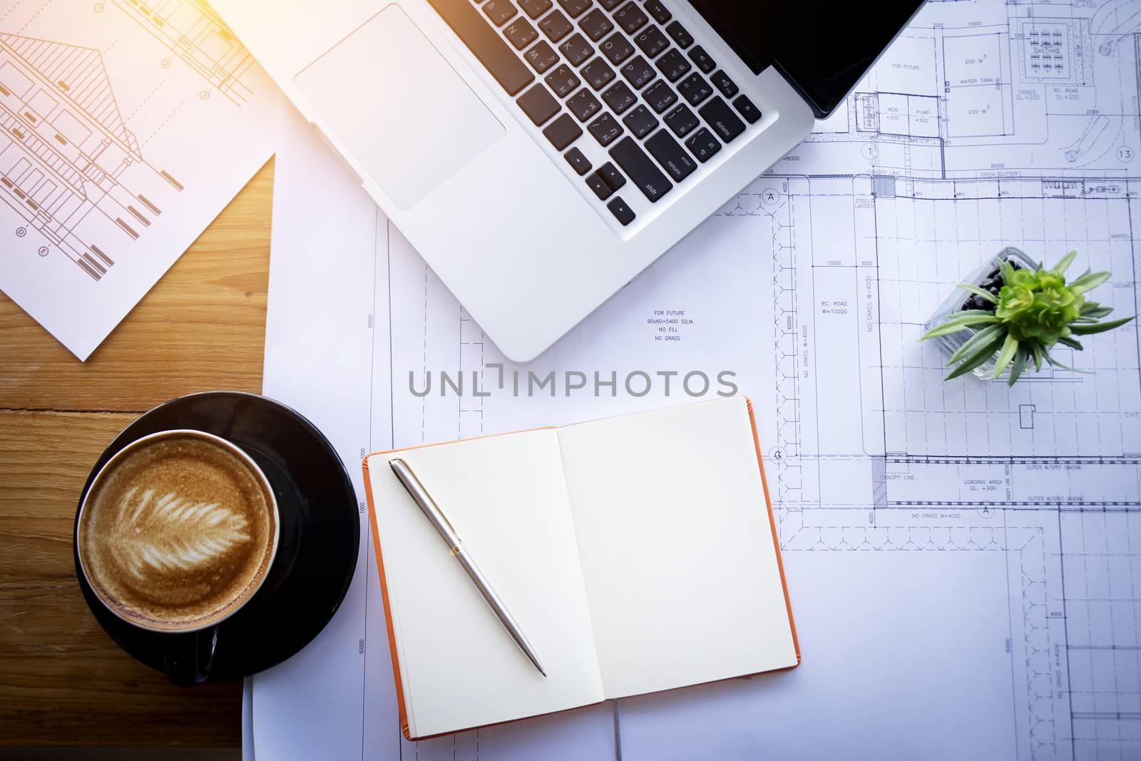 Abstract architectural drawing , sketch , plan background : architecture blueprint for detail of project and modern house on table in modern office with notebook , coffee , cactus ,laptop. film effect