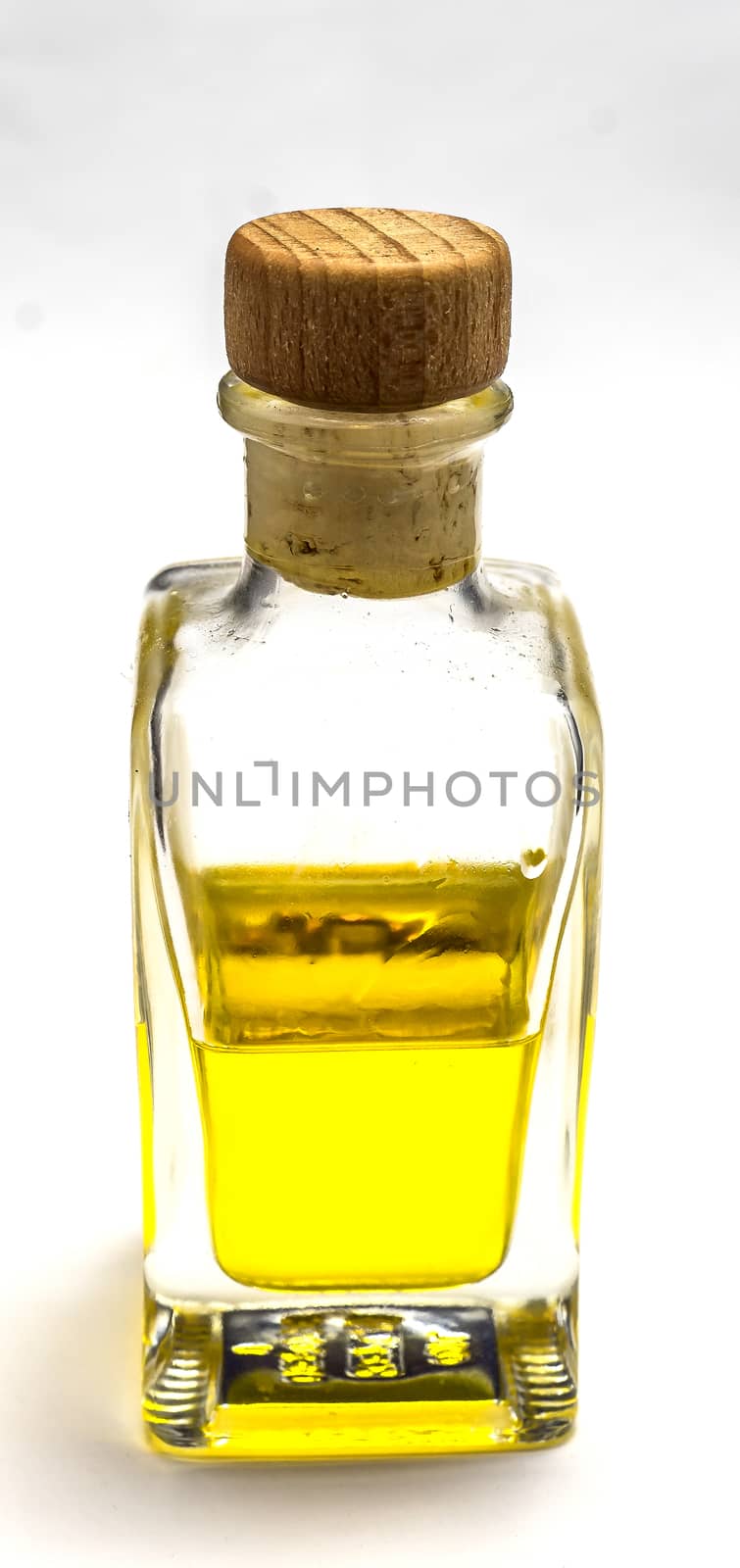 Semi-filled bottle with a yellow liquid and a cork stopper in front of a white background