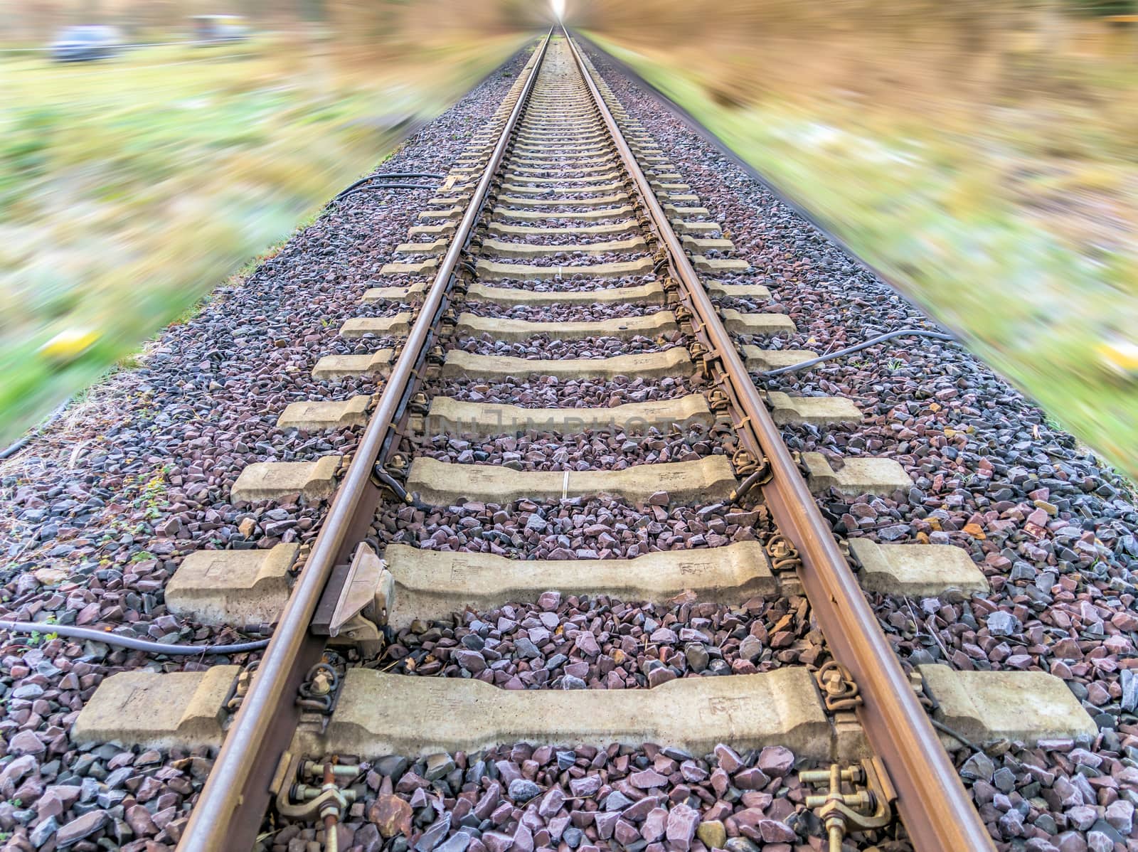 Abstract post-processed photograph of railroad tracks with blurred landscape, central perspective, blurry