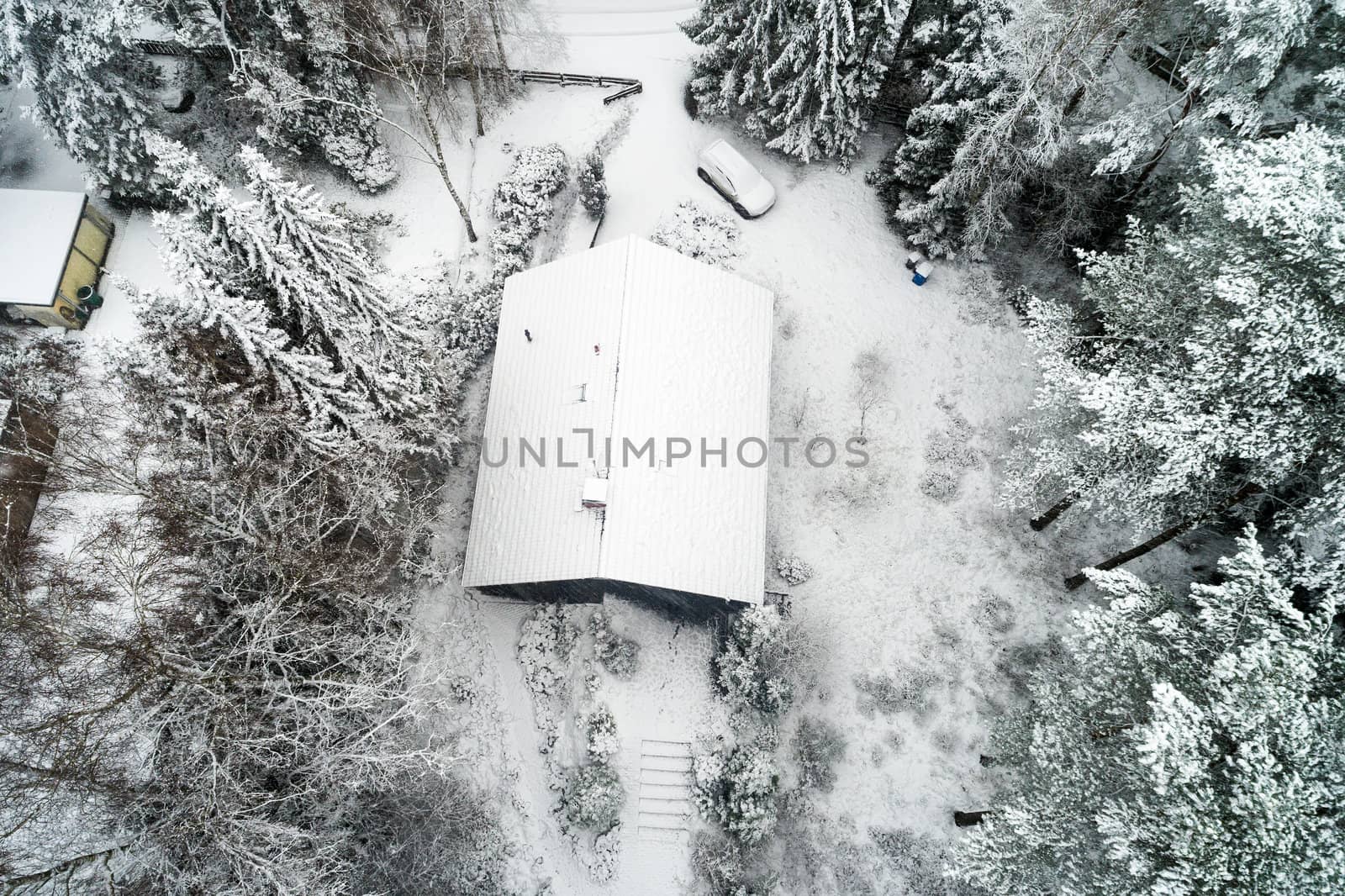 Family house in a forest after the first snowfall, aerial view with drone