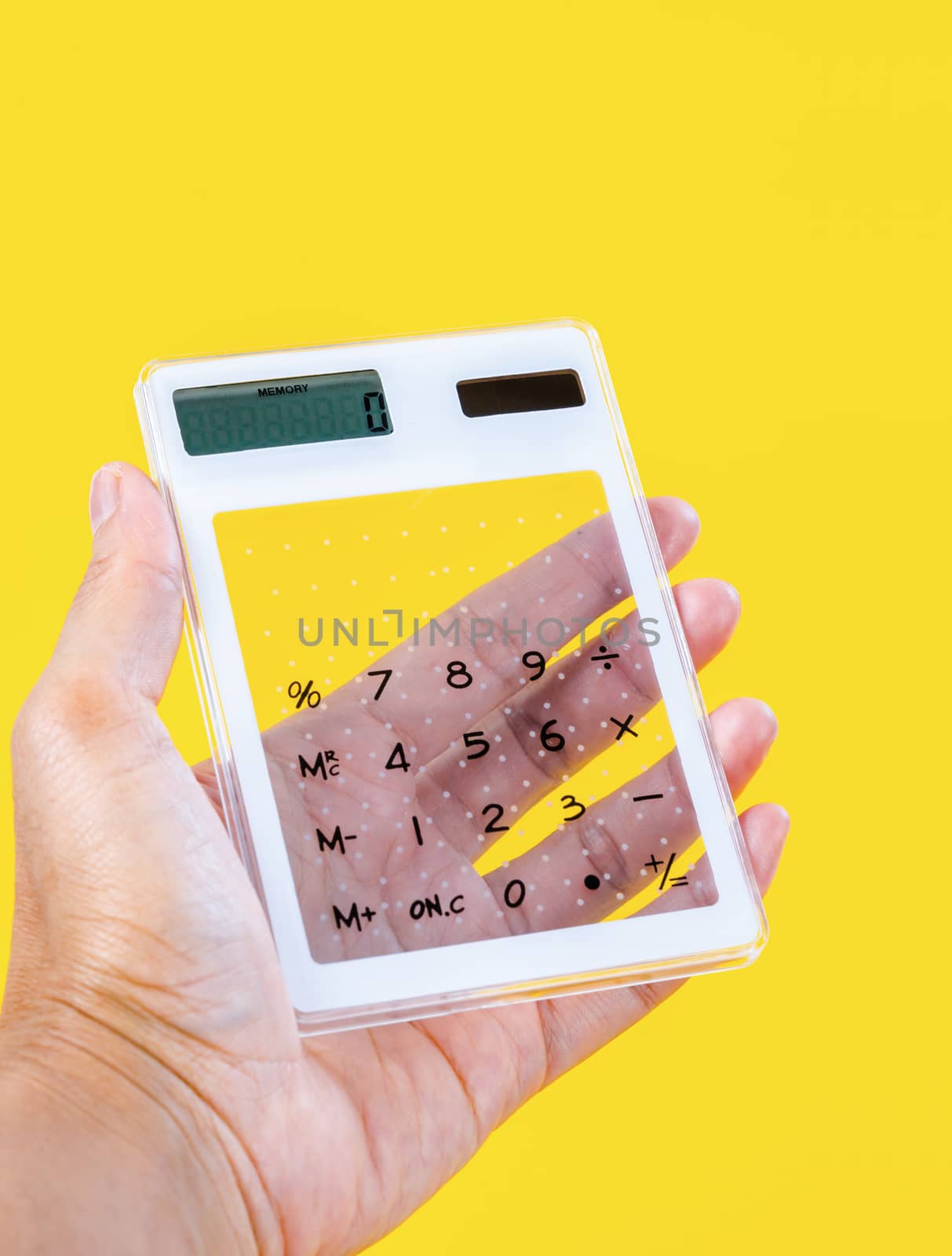 Hand showing digital calculator on yellow background.