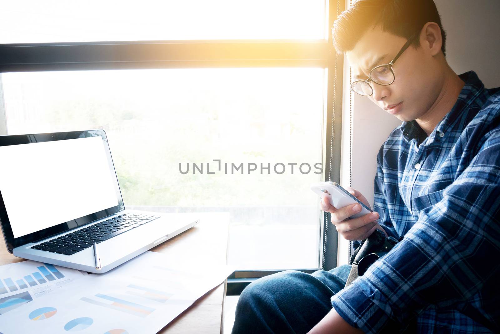 Business accounting people, saving, finance , economy concept. Serious Asian businessman using smartphone with paperwork, documents for statistic charts and graphs on table. Asia male model in his 30s by asiandelight