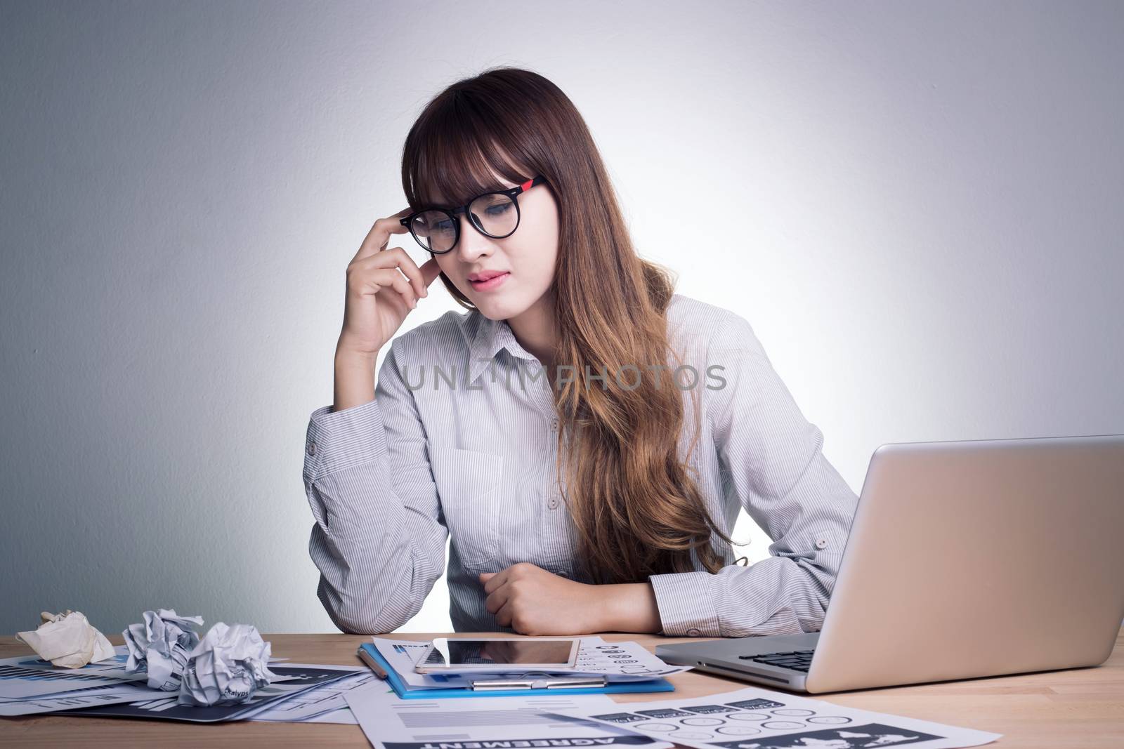 Feeling sick , stressed and tired. Stress young business woman of working age is working on a wooden table at her working place in office feel under pressure. Asian woman model in her 30s by asiandelight