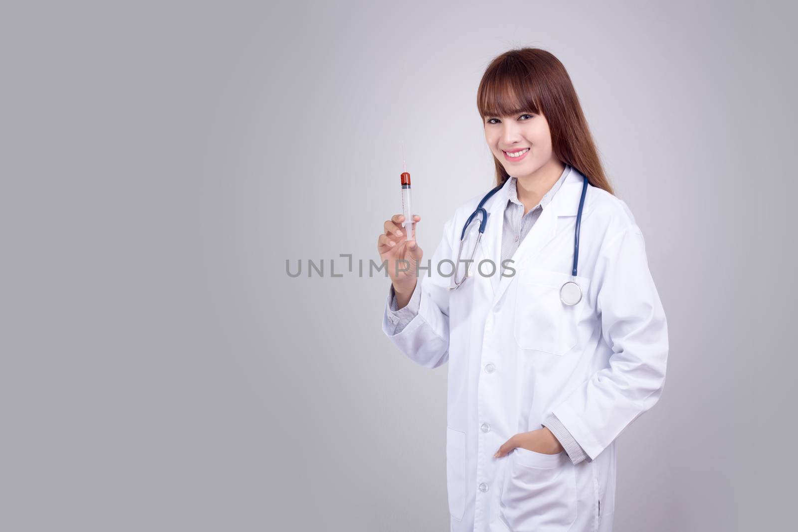 Healthy concept : Young Asian doctor with hypodermic syringe in hand isolate on grey background. Doctor , clinic , hospital poster and advertising with copy space for text by asiandelight