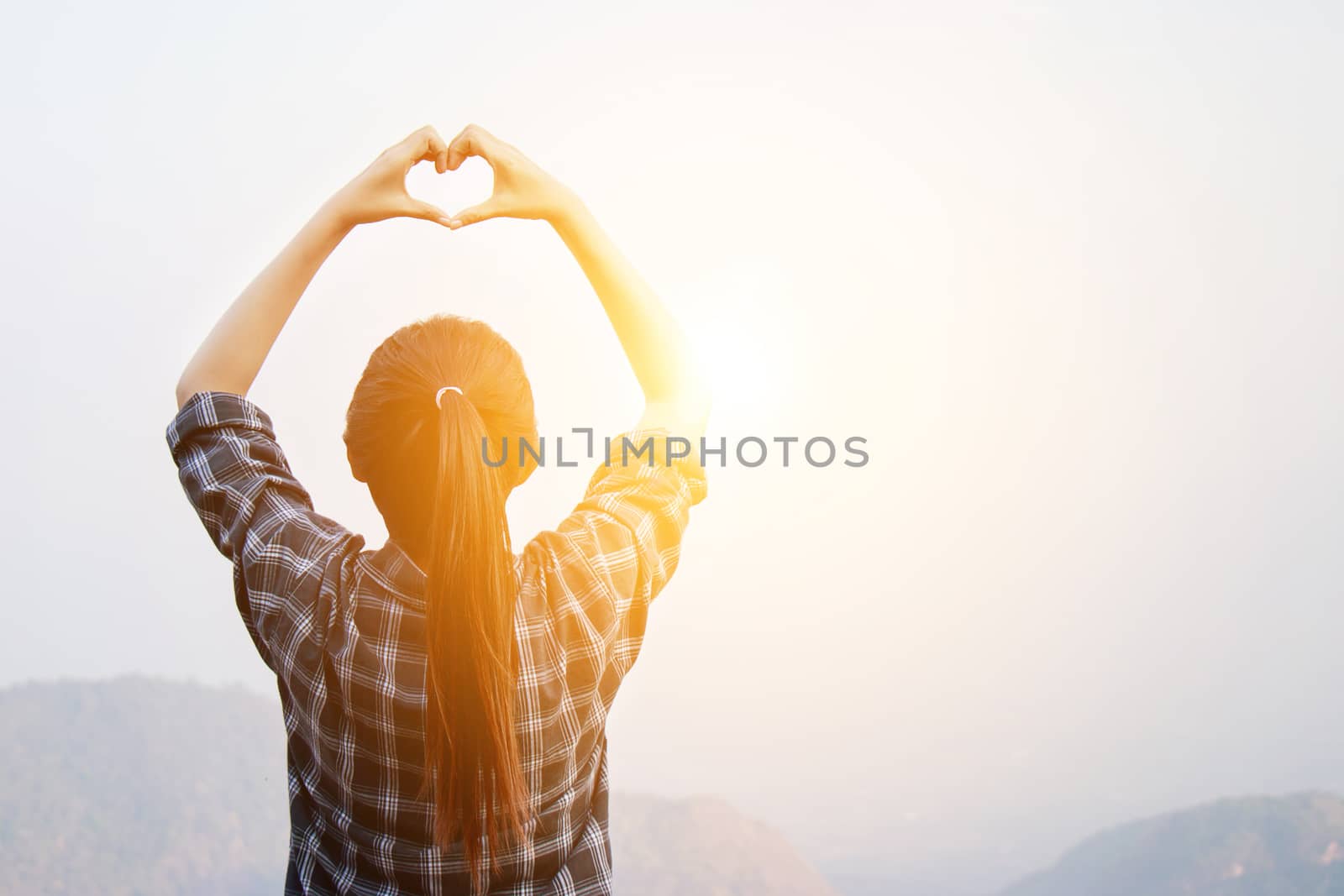 I love travel concept : Freedom traveler woman standing with heart shaped hands and enjoy a wonderful nature at sunrise with morning light effect