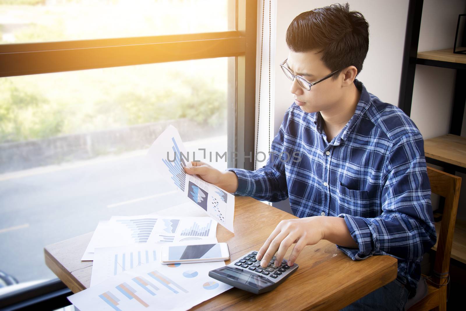 Business accounting people, saving, finance and economy concept. Serious Asian businessman using calculator for calculations documents , charts and graphs. Asia male model in his 30s