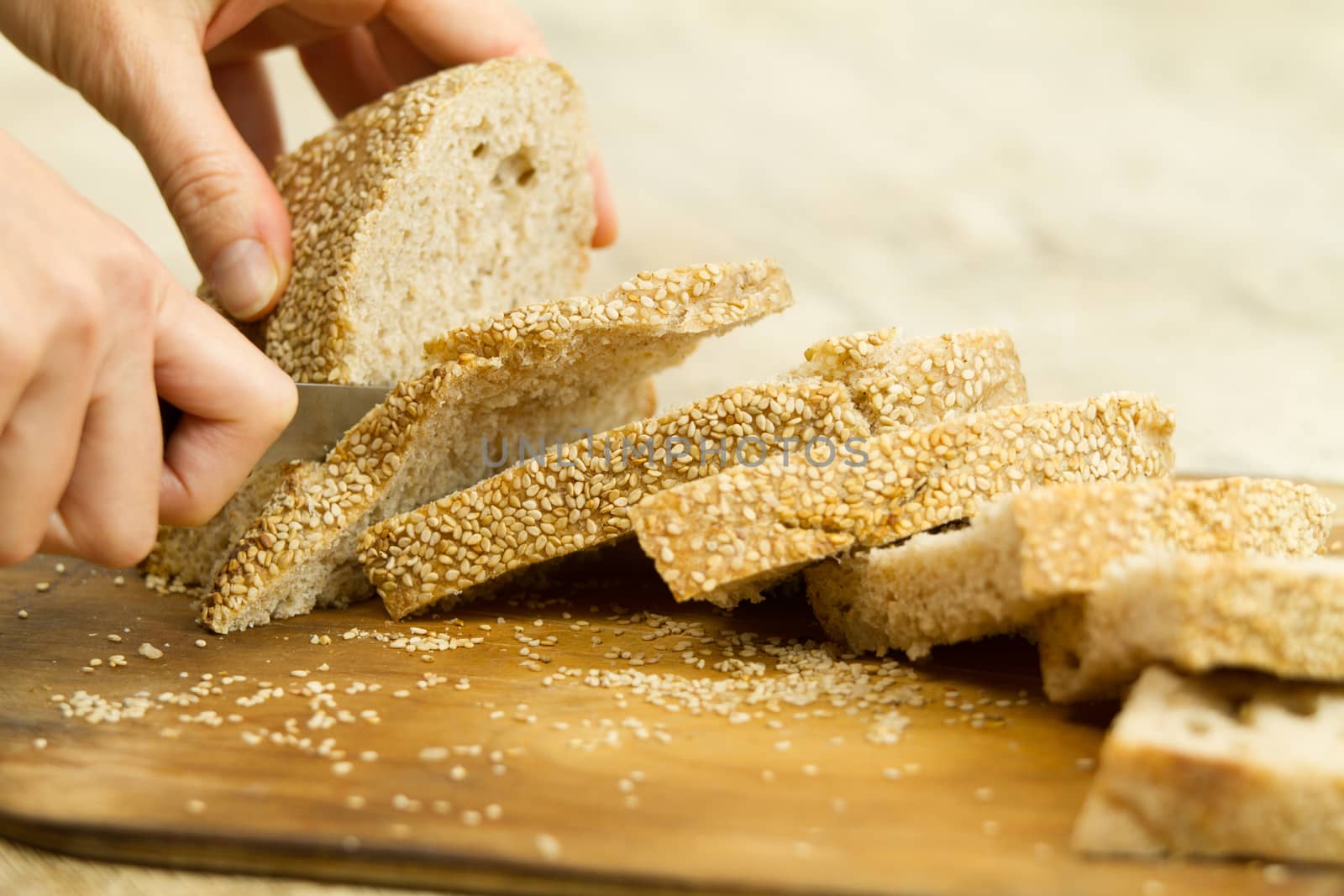 Close up of woman hands slicing a loaf of homemade bread with se