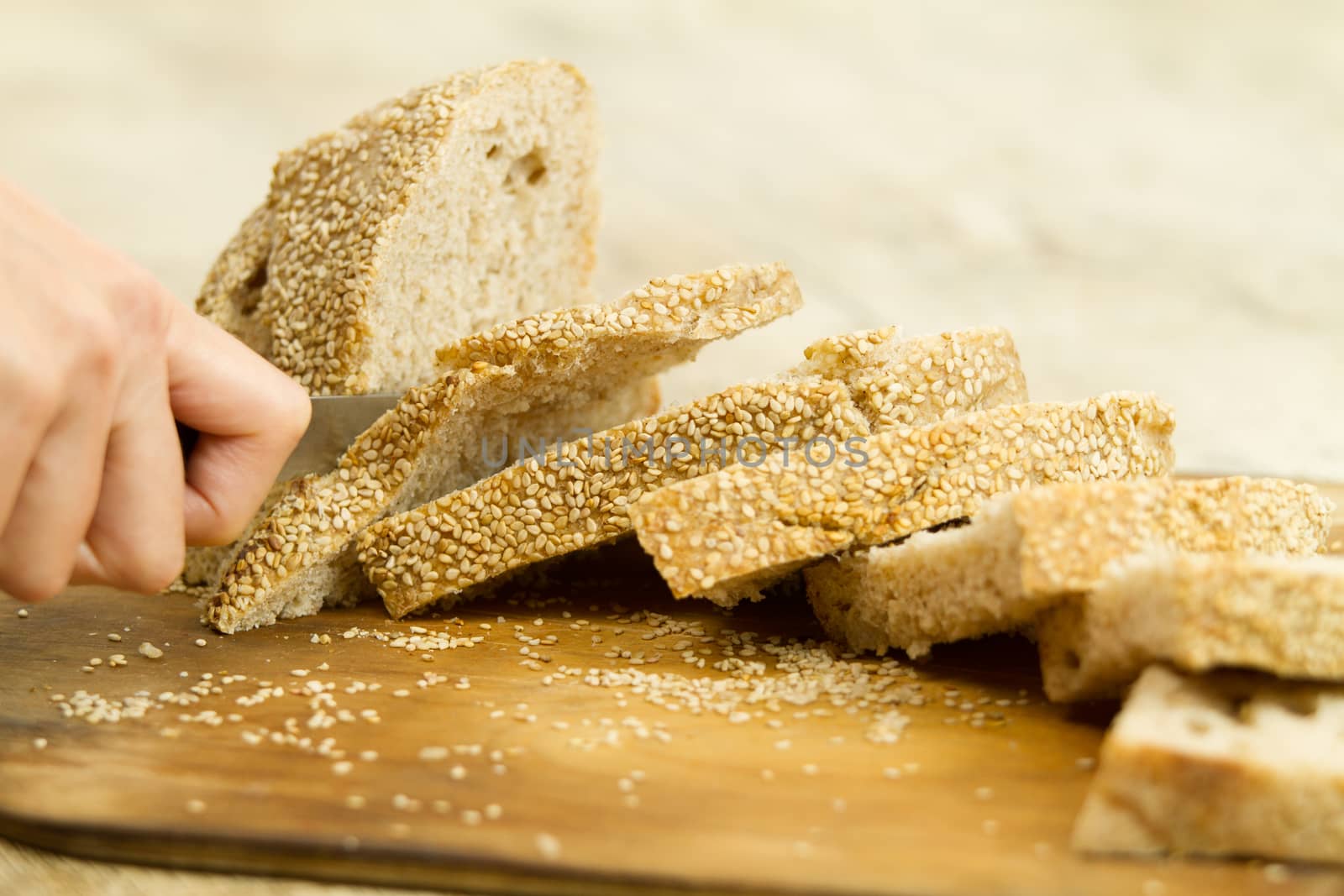 Close up of woman hands slicing a loaf of homemade bread with se