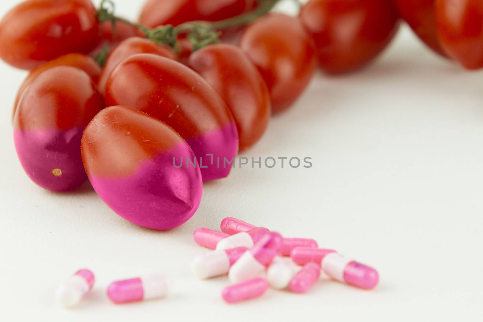 Concept: human GMO manipulation of nature and relative poisoned fruits. Close-up of three tomatoes contaminated by changing color from the medicines in front of it on a white background