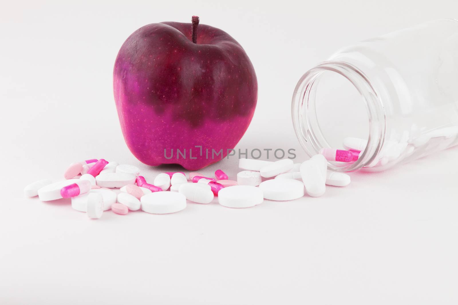Concept: human GMO manipulation of nature and relative poisoned fruits. Close-up of an apple contaminated by changing color from the medicines in front of it on a white background