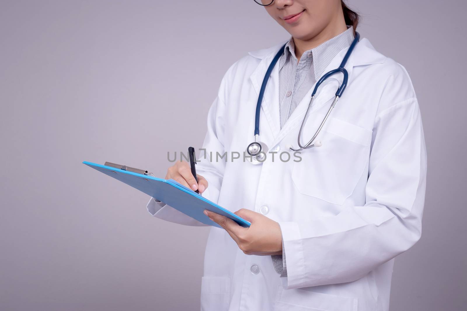 Healthy concept : Young Asian doctor writing on clipboard  for patient chart , anonymous face. Beautiful Asia female model in her 30s
