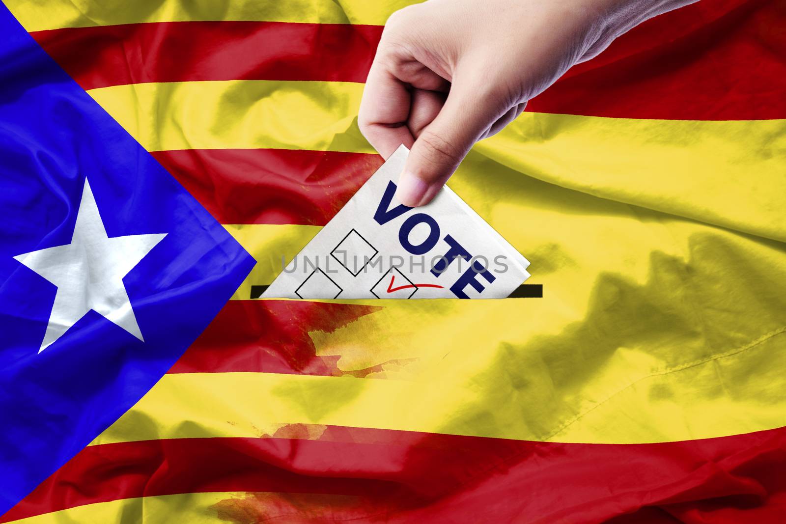 Vote referendum for Catalonia independence exit national crisis separatism risk : close up hand of a person casting a ballot at elections during voting on canvas Spain and Catalan flag background.
