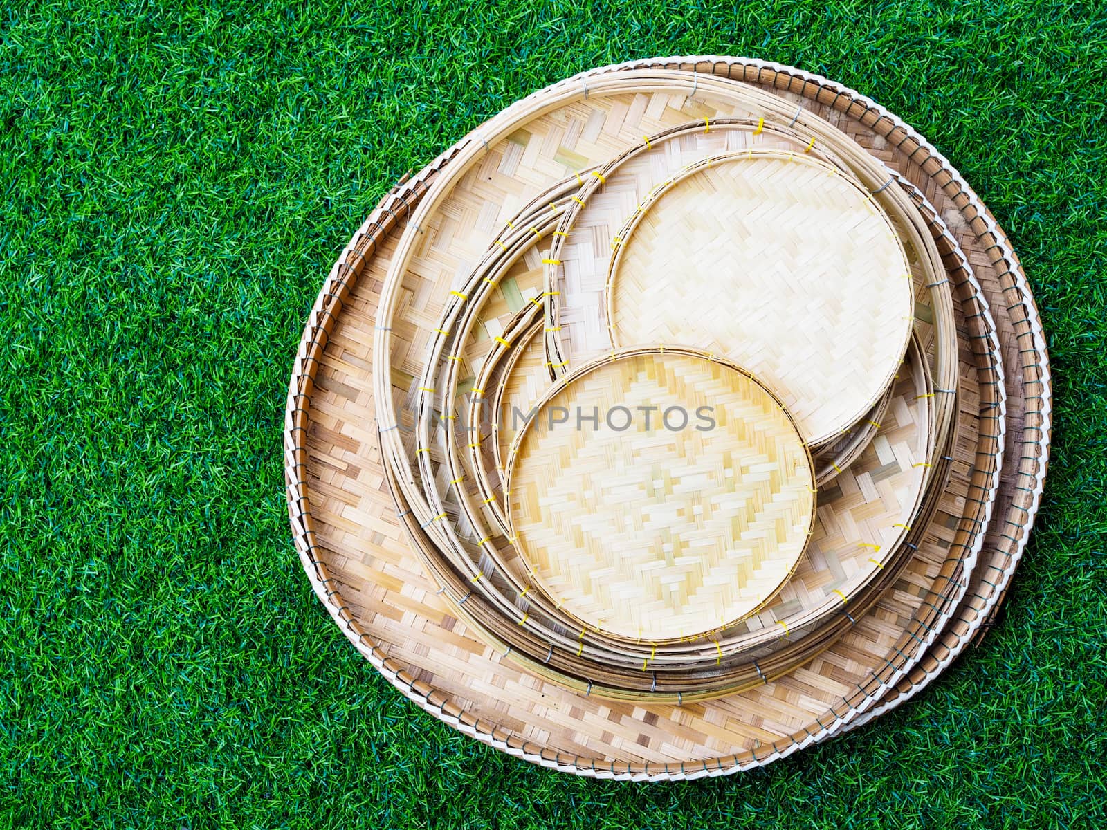 Above of set of bamboo weave trays, container for placing Thai food of many sizes isolated on green grass background.