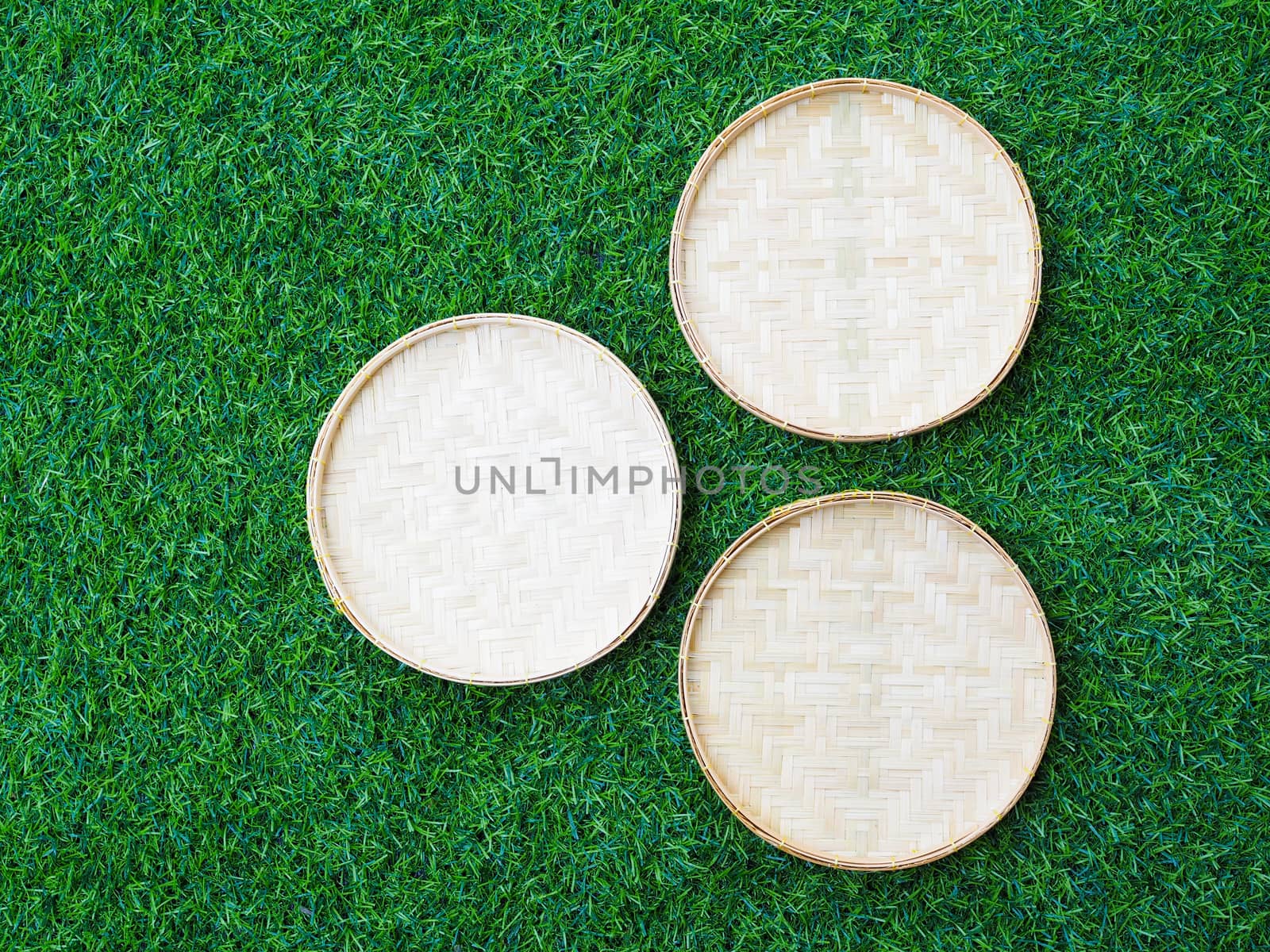 Traditional design of bamboo weave trays container isolated on green grass background.