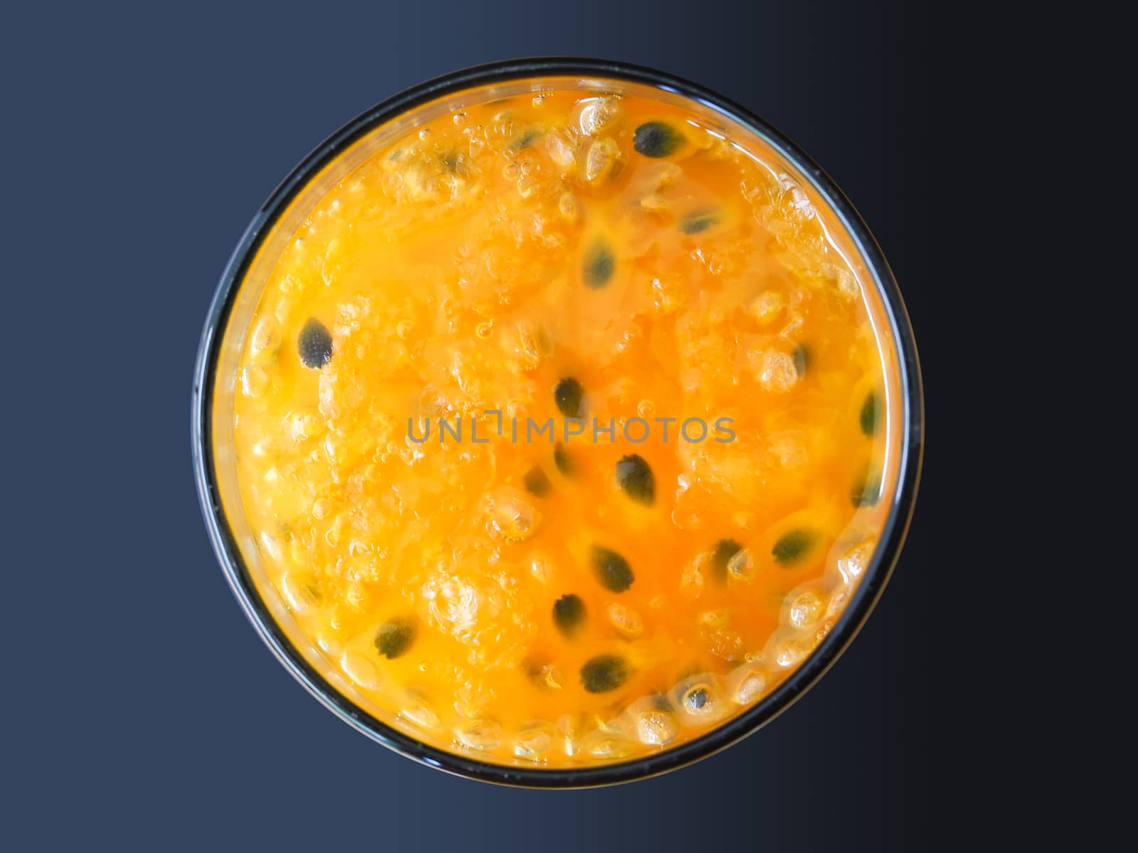 Top view of glass drink with yellow passion fruit juice and black seeds, fresh fruit juice in summer isolated on dark background.