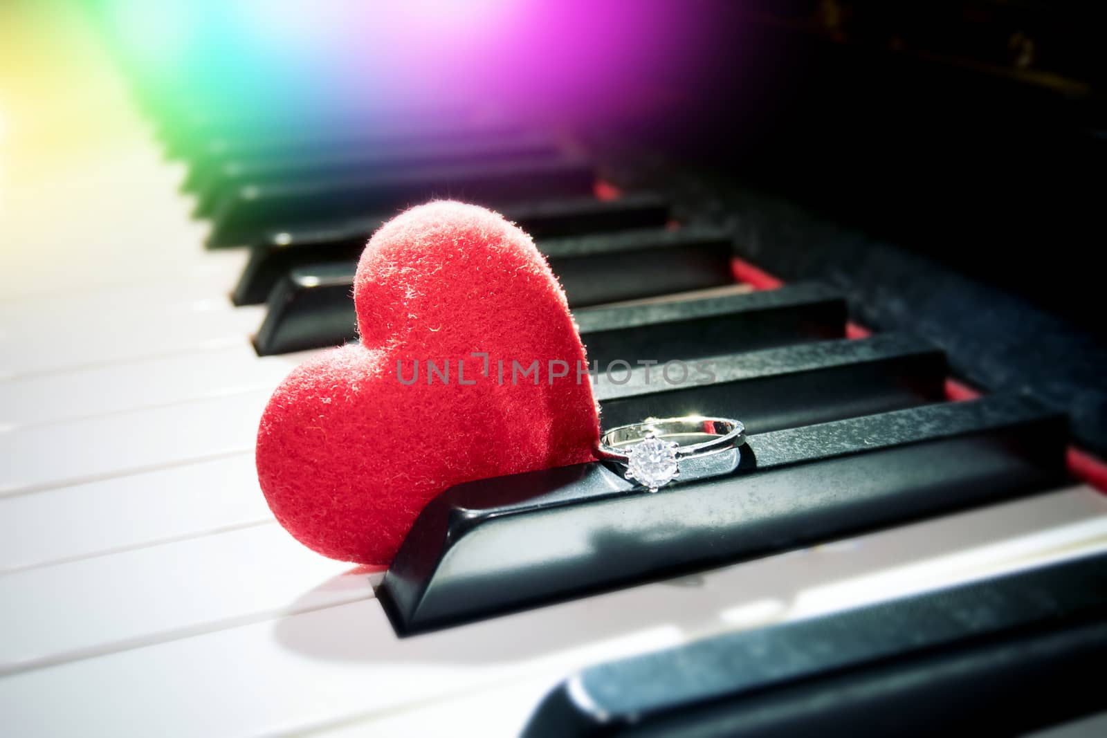 romantic relationship concept : velvet red heart and shiny diamond ring on the piano by asiandelight