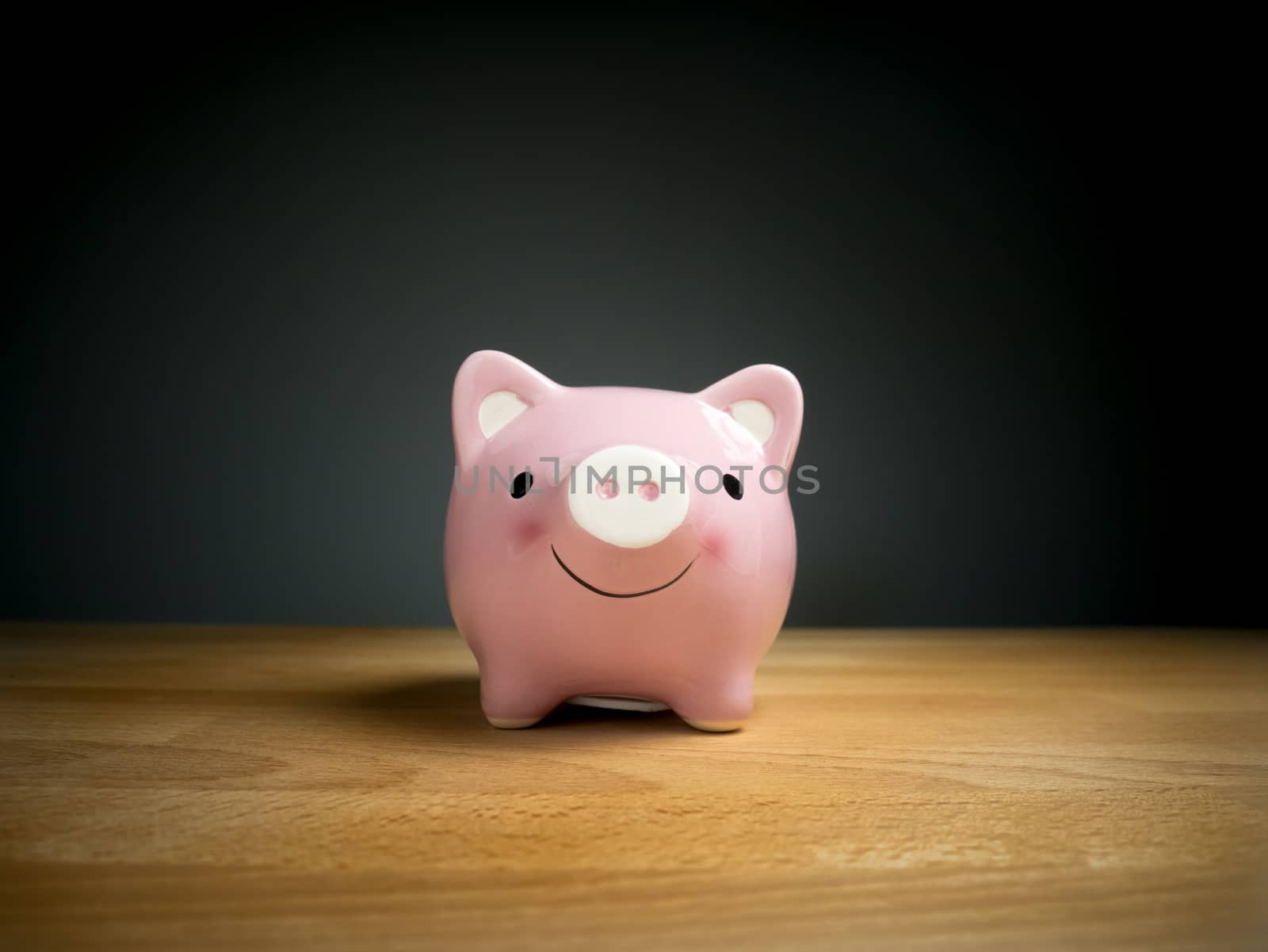 Piggy Bank, Savings, Currency concept : Pink piggy bank with smile face on wooden table with black background by asiandelight