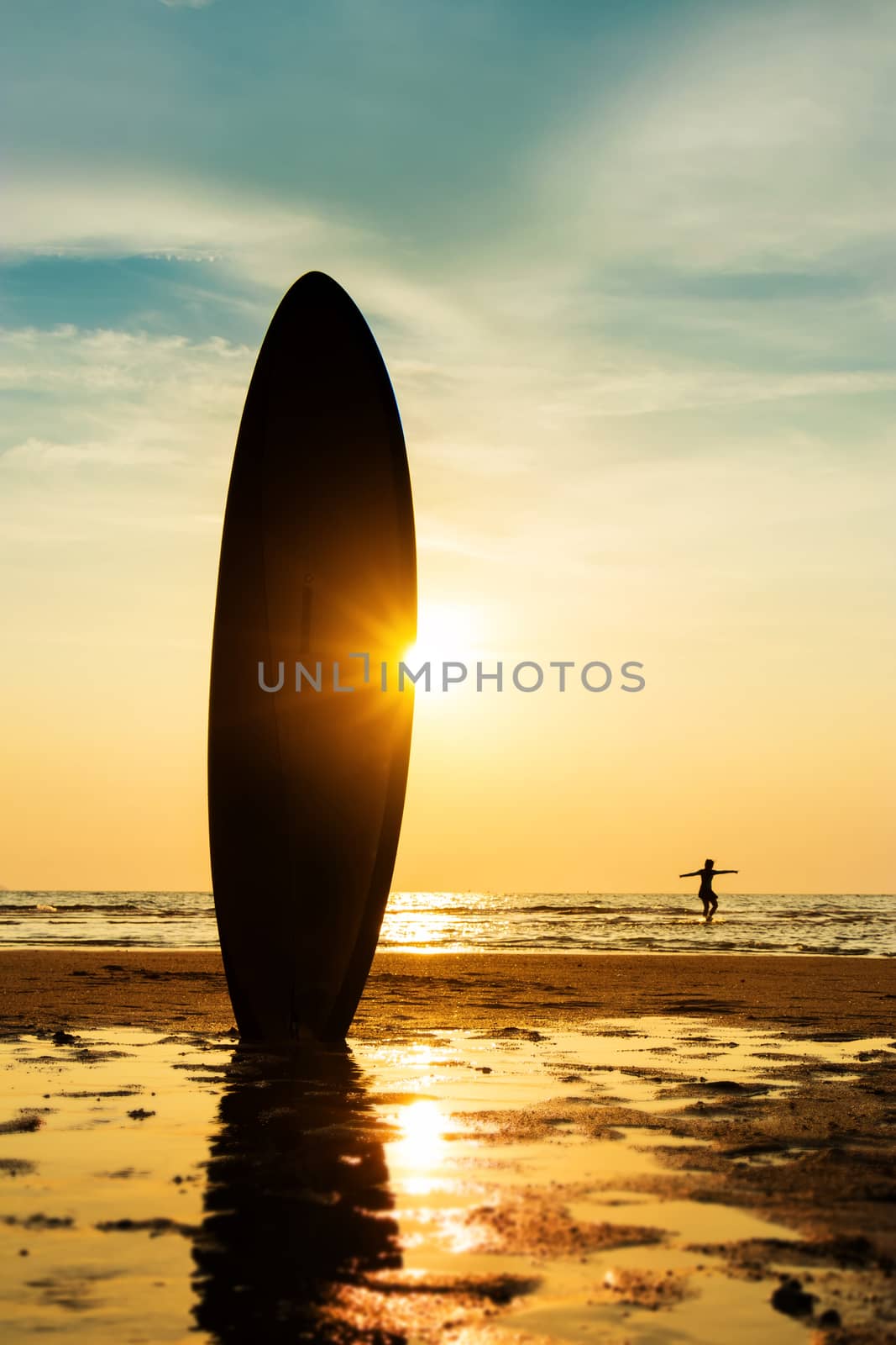 Silhouette of surf man surfing with a surfboard on the seashore beach at sunset time. Handsome Asia man model in his 20s. by asiandelight