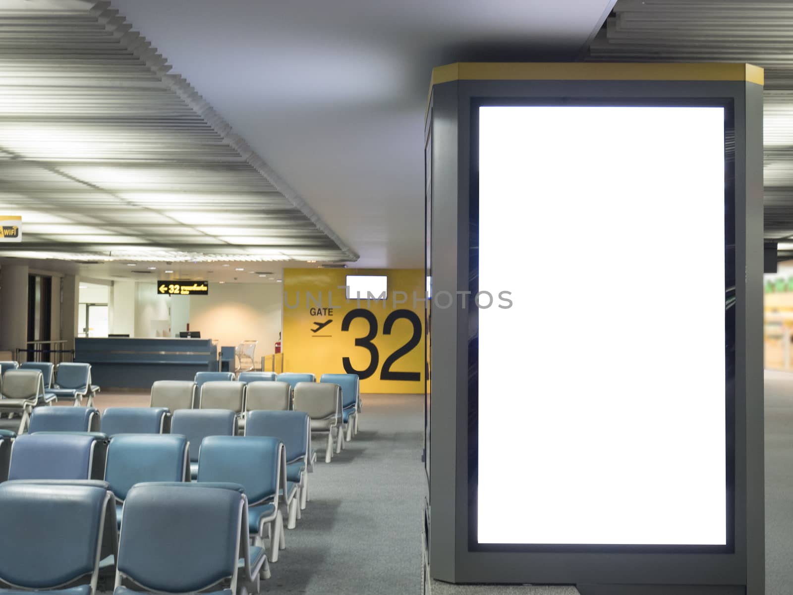 Airport advertising board sign concept : Big blank white advertising billboard screen frame at the airport with copy space in public place , passenger waiting seat and airport gate number background by asiandelight