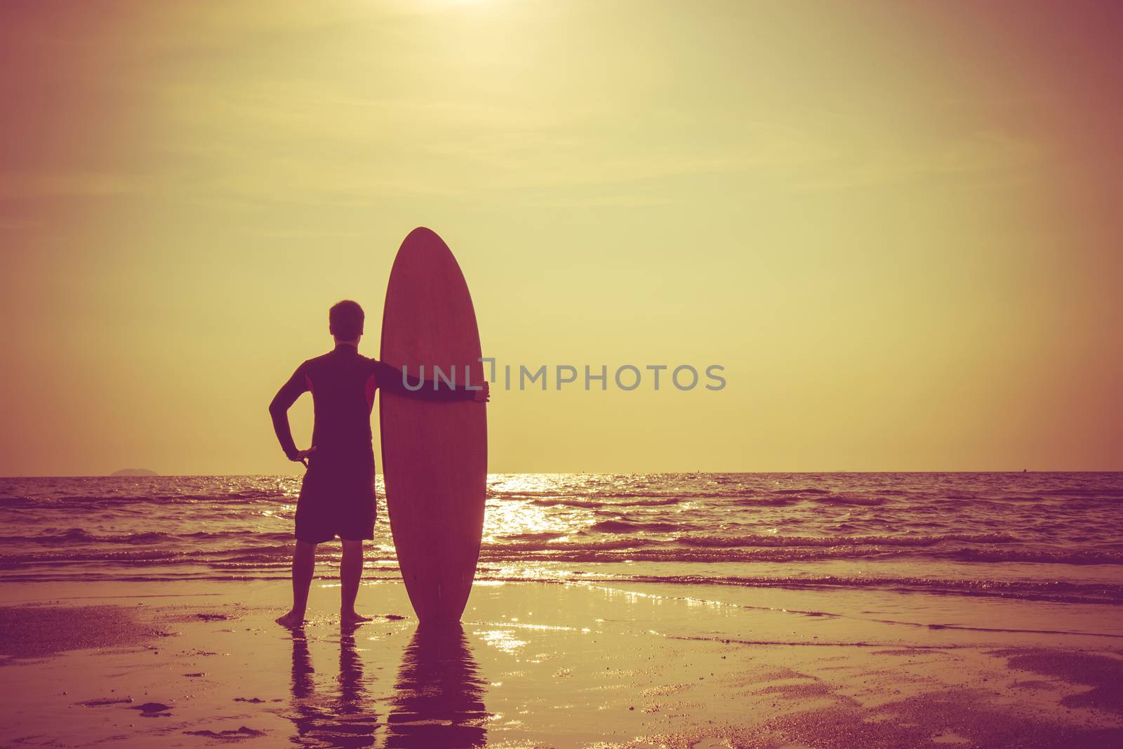 Silhouette of surf man stand with a surfboard. Surfing at sunset beach. Outdoor water sport adventure lifestyle.Summer activity. Handsome Asia male model in his 20s.