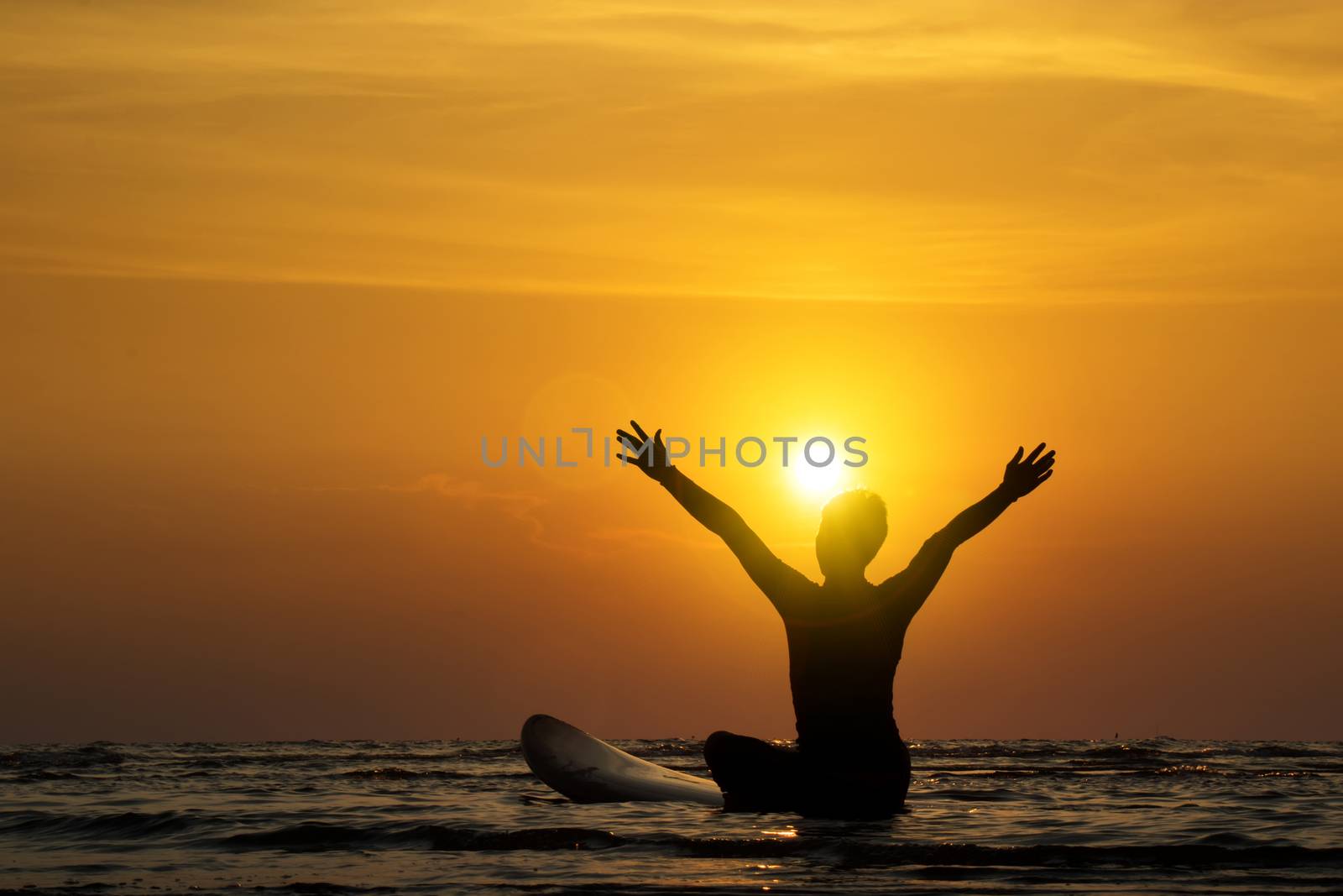 Silhouette of surf man sit on a surfboard, open arms. Surfing at sunset beach. Outdoor water sport adventure lifestyle.Summer activity. Handsome Asia male model in his 20s. by asiandelight