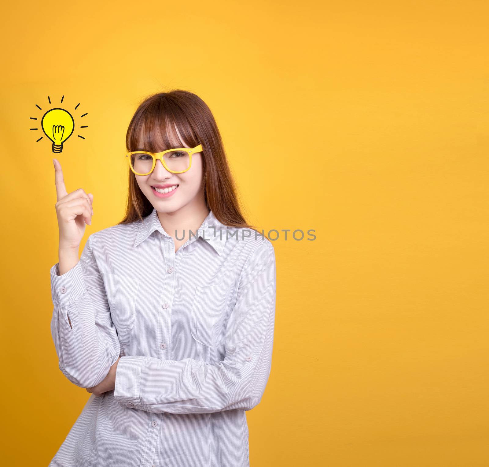 Business Asian woman with yellow vintage glasses stand and have idea lamp bulb light on fingertip, yellow background with copy space for design for poster and advertising text. Asia model in her 20s.