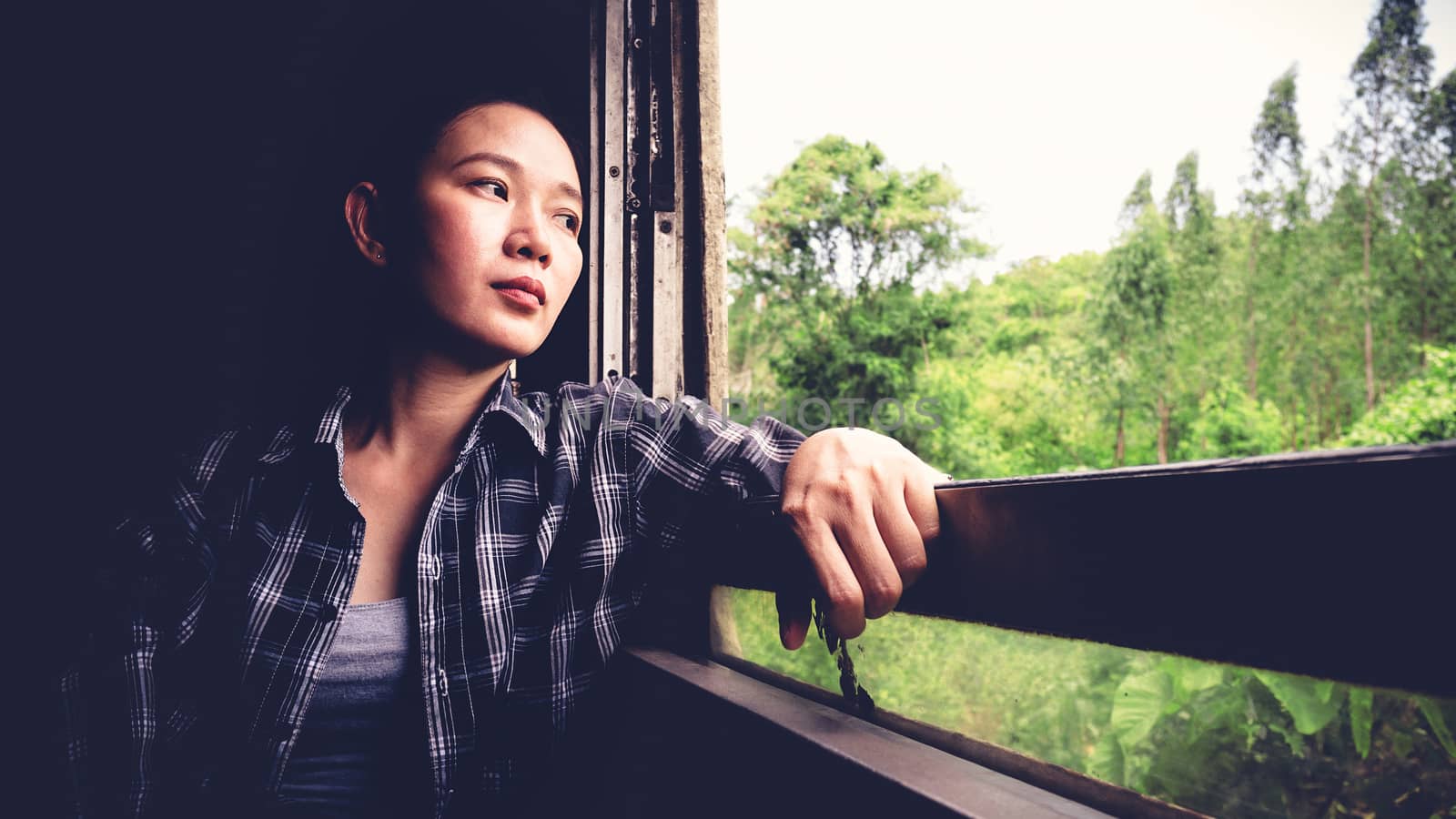 Backpacker tired from travel transportation. Young pretty Asia woman traveling to countryside by Thailand classic train sitting near the window. vintage filter. Beautiful Asian female model in her 20s by asiandelight