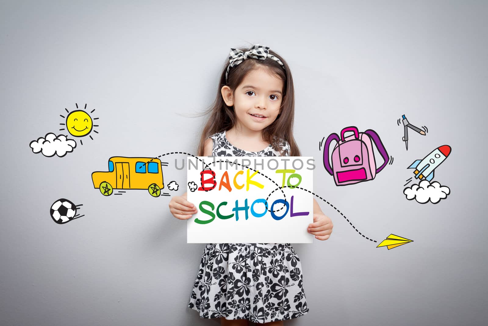 Back to school concept: Cheerful smiling little girl hold paper write back to school with colorful with cartoon around. Cute mixed race girl half Thai, half English model 3 years old.
