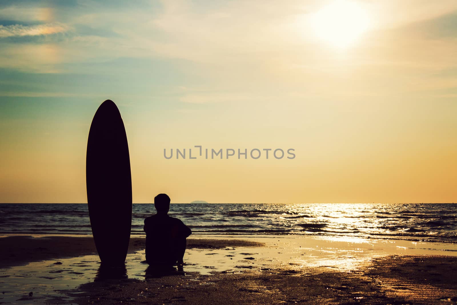 Silhouette of surf man sitting with a surfboard on the seashore beach at sunset time. Handsome Asia man model in his 20s. by asiandelight