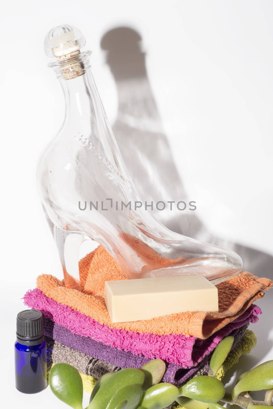 glass shoe and soap on facecloths of various shades with natural green plant