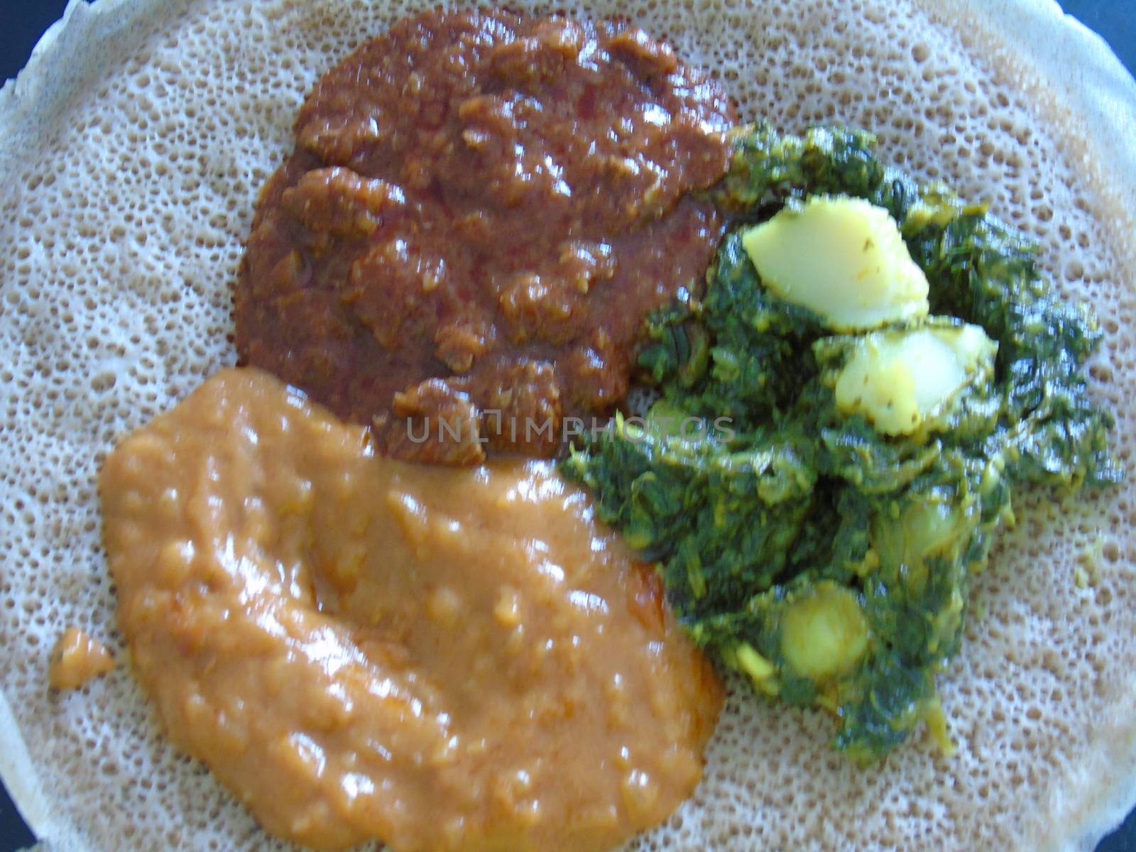 Asmara, Eritrea - 08/05/2020: Ethiopian and Eritrean food, assortment of main dishes. Injera is a sourdough flatbread made from teff flour. It is the national dish of Ethiopia, Eritrea.