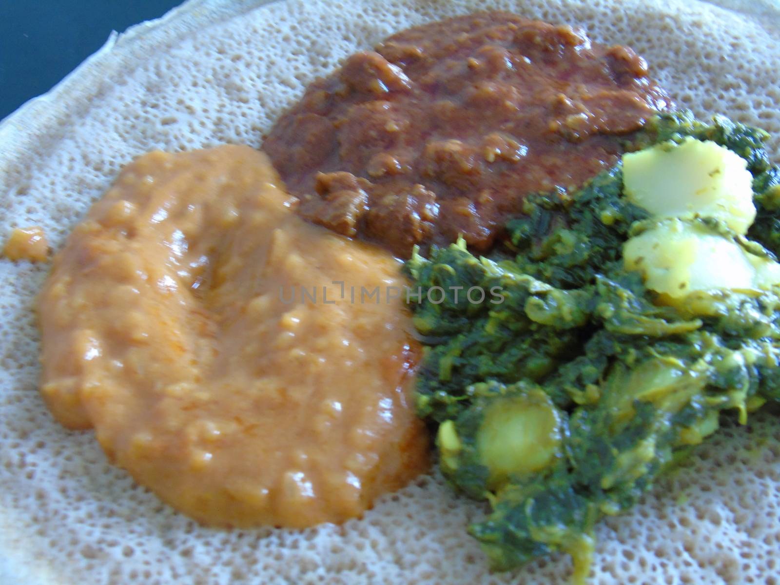 Asmara, Eritrea - 08/05/2020: Ethiopian and Eritrean food, assortment of main dishes. Injera is a sourdough flatbread made from teff flour. It is the national dish of Ethiopia, Eritrea.