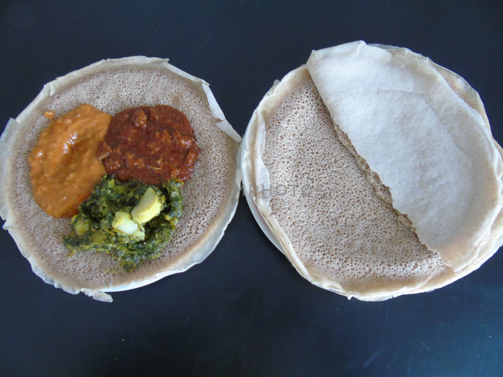 Asmara, Eritrea - 08/05/2020: Ethiopian and Eritrean food, assortment of main dishes. Injera is a sourdough flatbread made from teff flour. It is the national dish of Ethiopia, Eritrea.