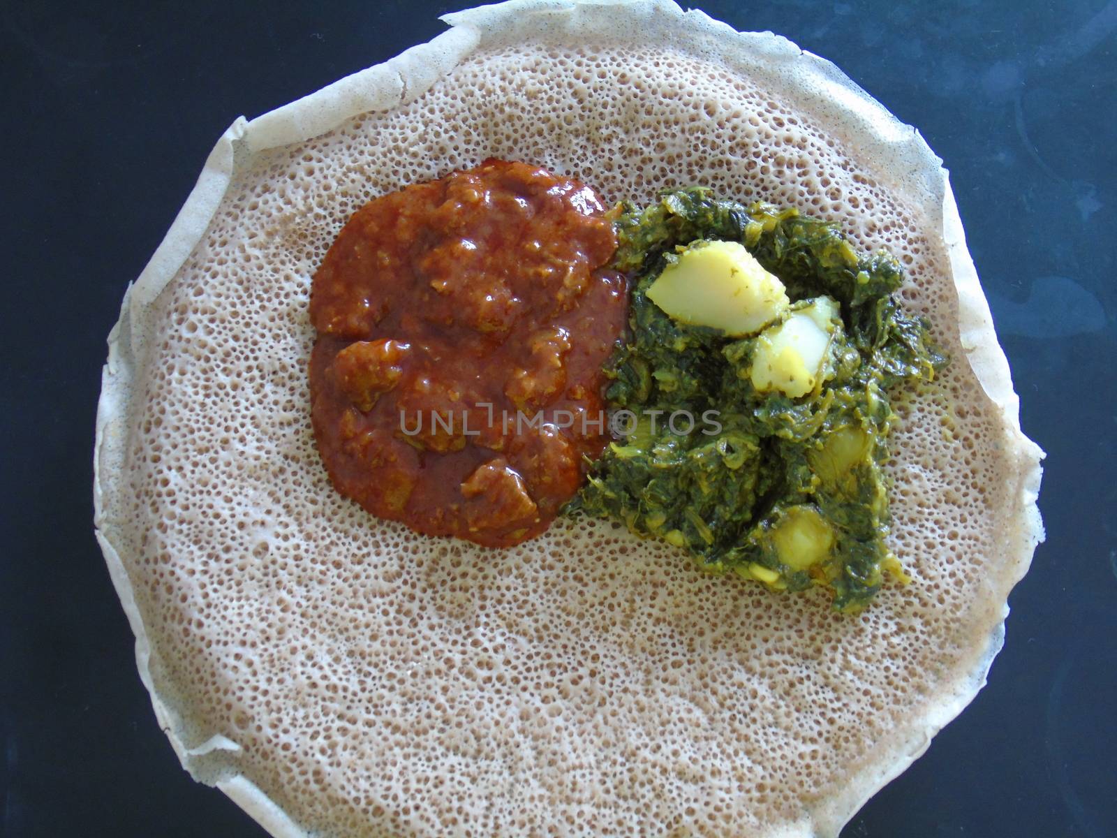 Asmara, Eritrea - 08/05/2020: Ethiopian and Eritrean food, assortment of main dishes. Injera is a sourdough flatbread made from teff flour. It is the national dish of Ethiopia, Eritrea.