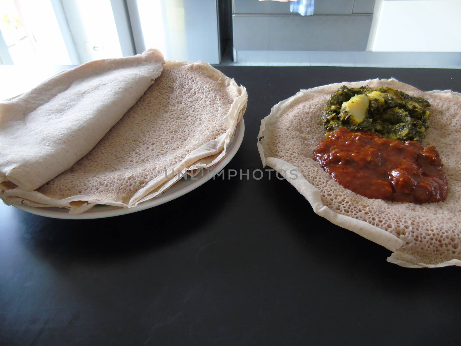 Asmara, Eritrea - 08/05/2020: Ethiopian and Eritrean food, assortment of main dishes. Injera is a sourdough flatbread made from teff flour. It is the national dish of Ethiopia, Eritrea.