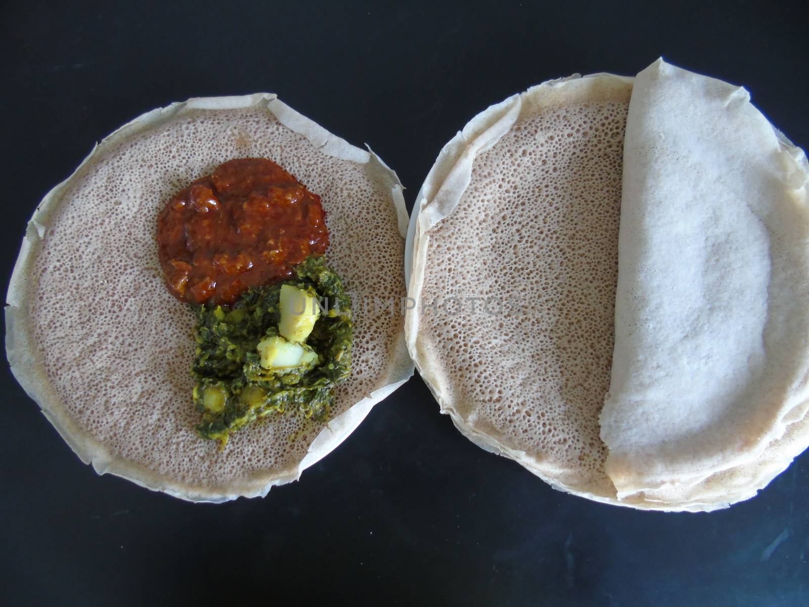 Asmara, Eritrea - 08/05/2020: Ethiopian and Eritrean food, assortment of main dishes. Injera is a sourdough flatbread made from teff flour. It is the national dish of Ethiopia, Eritrea.