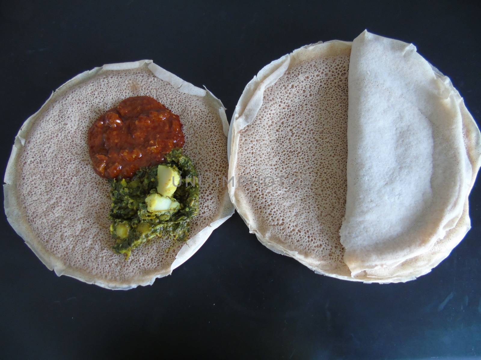 Asmara, Eritrea - 08/05/2020: Ethiopian and Eritrean food, assortment of main dishes. Injera is a sourdough flatbread made from teff flour. It is the national dish of Ethiopia, Eritrea.